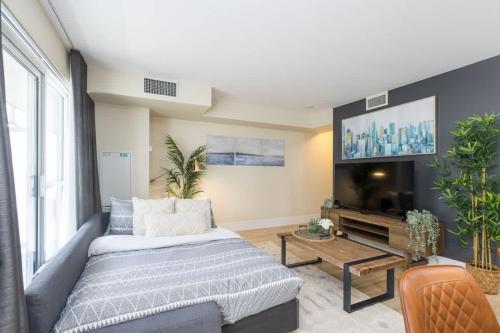 a living room with a couch and a flat screen tv at Modern 1BR Condo w Patio in Vibrant Front Street in Toronto