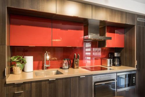 a kitchen with red cabinets and a stainless steel sink at Modern 1BR Condo w Patio in Vibrant Front Street in Toronto