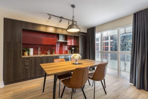 a kitchen and dining room with a wooden table and chairs at Modern 1BR Condo w Patio in Vibrant Front Street in Toronto