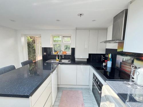 a kitchen with white cabinets and black counter tops at Exquisite 2 Bedroom Fully Furnished Annex in Bradenham