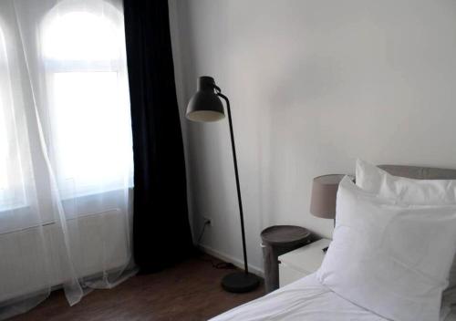 a bedroom with a bed and a lamp next to a window at ChillingHouse Apartments Siegburg in Siegburg