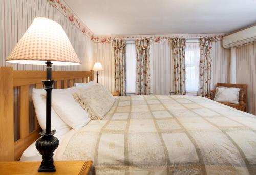 a bedroom with a bed with a lamp on a table at The Monadnock Inn in Jaffrey