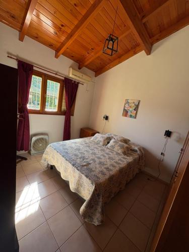 Un dormitorio con una cama y un techo de madera. en Casa Zeballos, en Sunchales