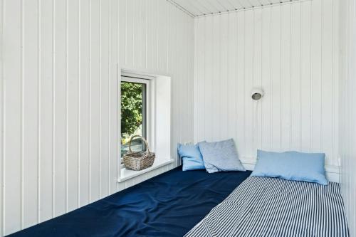 a room with two blue pillows and a window at Cabin By Forest And Beach In Havhusene in Hornslet