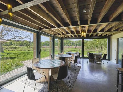 a room with tables and chairs and large windows at Villa Lactea in Schilde