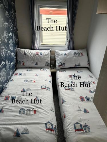 two twin beds in a room with the beach hit at CT12 The Beach Hut in Rhyl