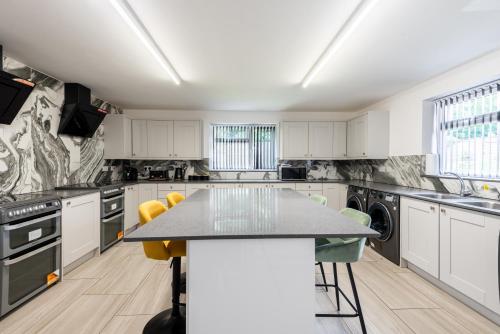 a kitchen with white cabinets and a table with yellow chairs at Sleek Luxe Room - Contractor and Holiday Stay in Coventry