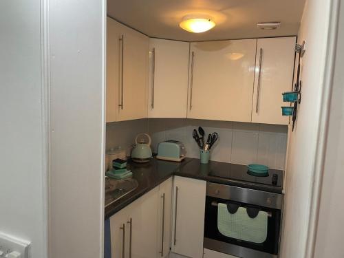 una piccola cucina con mobili bianchi e una stufa di Quirky Cottage Central Bathgate a Bathgate