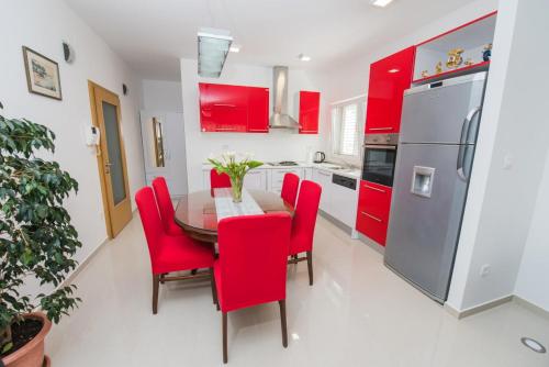 een keuken met rode kasten en een tafel met rode stoelen bij Apartments Blaf in Podstrana