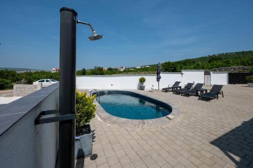 a swimming pool on a patio with chairs and a lamp at Family friendly house with a swimming pool Maslenica, Novigrad - 23719 in Jasenice