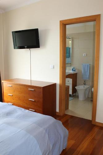 a bedroom with a bed and a bathroom with a television at Cozy and Bright Apartment in Machico