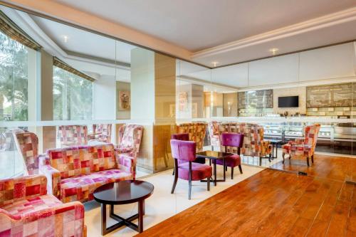 a lobby with chairs and tables and a kitchen at Gulf Hotel Bahrain Convention and SPA in Manama