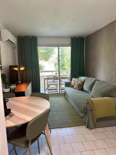 a living room with a couch and a table at L'appartement Vert, Piscine, 750m de la Plage in Cavalaire-sur-Mer
