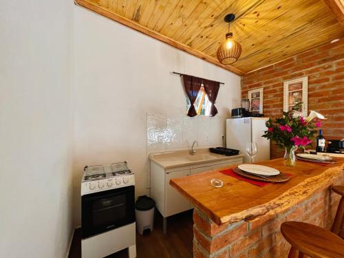 a kitchen with a counter and a stove and refrigerator at Chalé com lareira pertinho de Monte Verde in Camanducaia