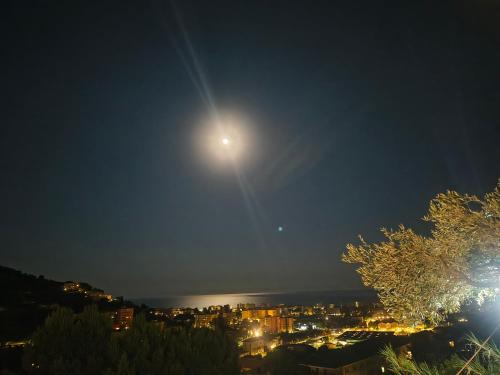 a full moon rising over a city at night at Casa indipendente Roque Vista al mar con parking gratuito in Vallecrosia