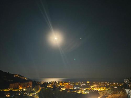 a full moon rising over a city at night at Casa indipendente Roque Vista al mar con parking gratuito in Vallecrosia