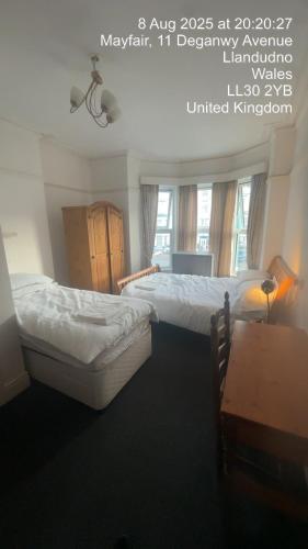 two beds in a bedroom with a poster for a room at Mayfair House in Llandudno