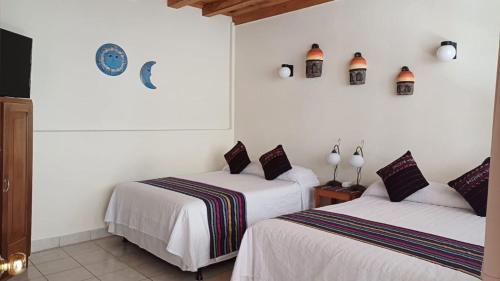 two beds in a room with white walls at Hotel El Recreo Lanquín-Champey in Lanquín