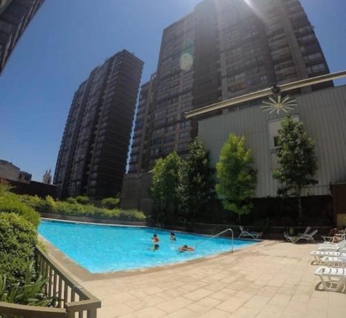 a group of people in a swimming pool with tall buildings at Never Give Up Suites in Santiago