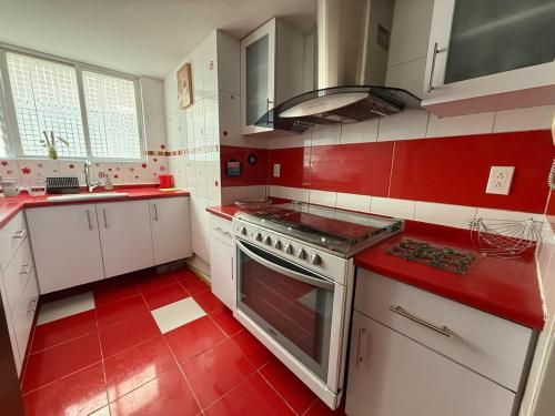 a red and white kitchen with a stove top oven at Vertiz apartment-hot tub - wifi- HiveNB in Mexico City