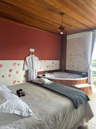 a bedroom with a large bed and a bath tub at Pousada Casa Pinha em Campos do Jordão in Campos do Jordão