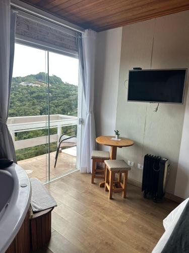 a room with a table and a large window at Pousada Casa Pinha em Campos do Jordão in Campos do Jordão