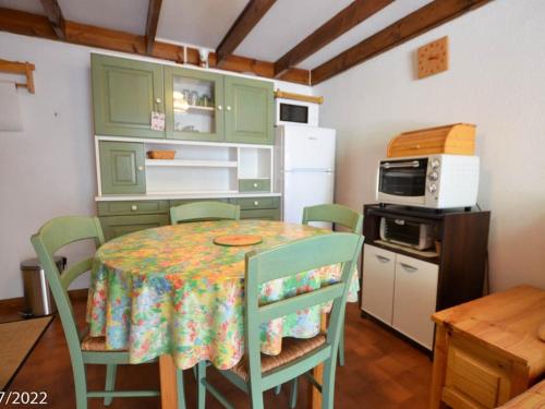 une cuisine avec une table avec des chaises et un micro-ondes dans l'établissement Maison T2 Bis avec Terrasse Privative, proche plage et commerces - LA PALMYRE - FR-1-705-27, à La Palmyre