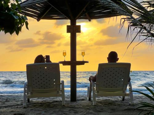 two people sitting in chairs on the beach watching the sunset at Suite Brisa Mulata en Laguna Beach, Tolú in Tolú