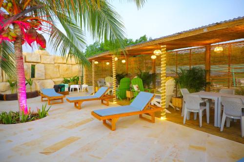 a patio with chairs and tables and a palm tree at Suite Brisa Mulata en Laguna Beach, Tolú in Tolú