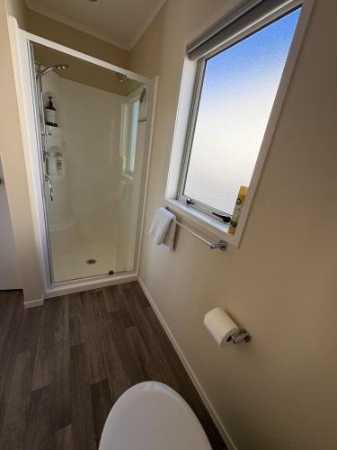 a bathroom with a toilet and a window at Havelock Cottage - Pukeko Nest in Havelock North