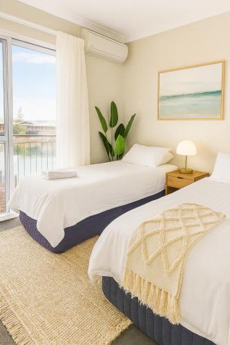 two beds in a bedroom with a window at Apollo Stayz Luxury Waterfront Home 57 - Pool - Spa - Jetty in Mandurah
