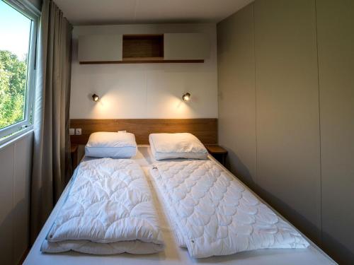 Dos camas en una habitación pequeña con ventana. en cozy chalet for couples, en Oostkapelle