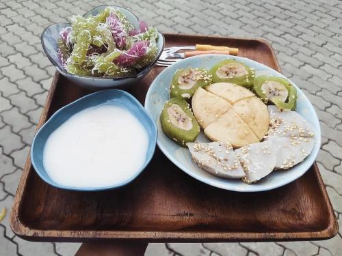 a tray with a plate of food and a bowl of salad at Here Library - A wooden home by the river with a library in Thốt Nốt