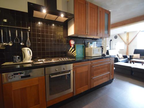 a kitchen with wooden cabinets and a stove top oven at Beautiful farmhouse in Wapse with fenced garden in Wapse