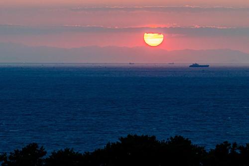 a sunset over the ocean with a boat in the water at Grampus Inn Shirahama in Shirahama