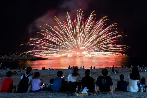 a group of people sitting on the beach watching a fireworks display at Grampus Inn Shirahama in Shirahama
