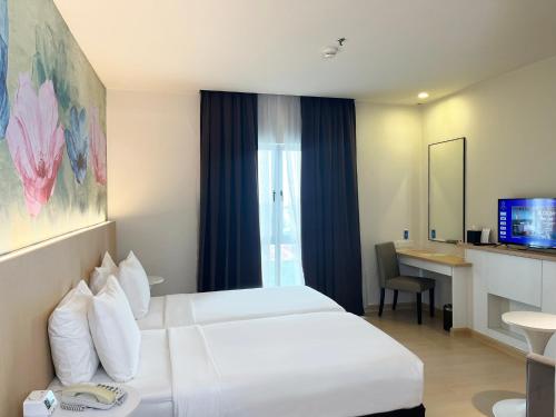 a hotel room with two white beds and a desk at Wyndham Garden i-City Shah Alam in Shah Alam