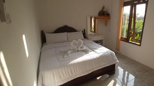 a bedroom with a bed with a white ribbon on it at The Carik Homestay in Tabanan