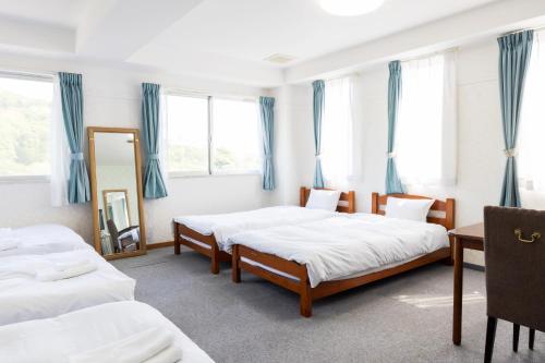 two beds in a room with blue curtains at Grampus Inn Shirahama in Shirahama