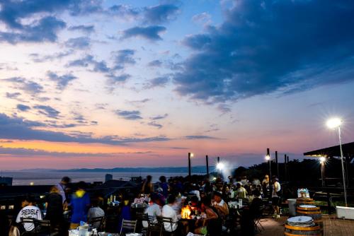 a crowd of people sitting in chairs watching the sunset at Grampus Inn Shirahama in Shirahama