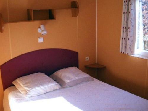 a bedroom with a bed with two pillows on it at Mobil-home confortable avec terrasse - 4 pers., 2 chambres - API-1-52-252 in Venterol