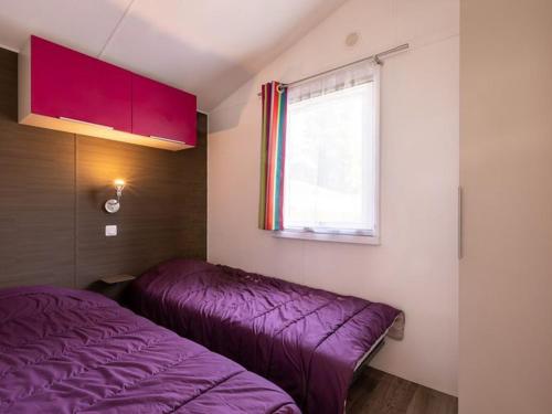 a bedroom with a purple bed and a window at Mobil home 2 chambres avec terrasse - API-1-52-478 in Brétignolles-sur-Mer