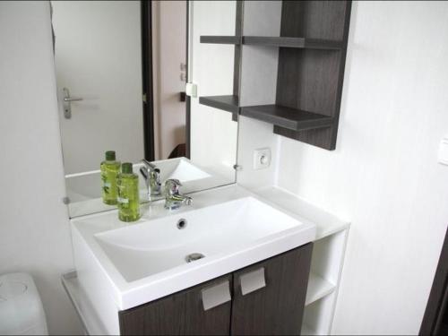 Un baño con un lavabo blanco y un espejo. en Mobil-home 25m² avec Terrasse à Brétignolles-sur-Mer - API-1-52-341, en Bretignolles-sur-Mer