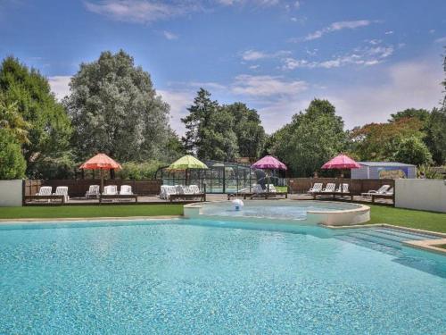 a swimming pool with chairs and umbrellas in a yard at Mobil-home 2 chambres avec terrasse - API-1-52-456 in La Mothe-Achard