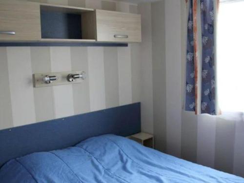 Un dormitorio con una cama con un edredón azul. en Mobil home 32m² avec terrasse pour 6 personnes - API-1-52-386, en Bretignolles-sur-Mer