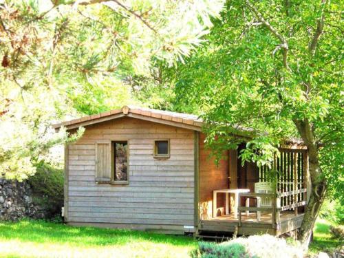 ein kleiner Schuppen mit einer Veranda und einem Stuhl darauf in der Unterkunft Chalet avec Terrasse et Salon de Jardin à Darbres - API-1-52-419 in Darbres