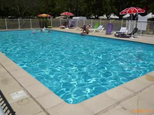 a large blue swimming pool with people in it at Chalet sur pilotis avec terrasse pour 4 personnes - API-1-52-496 in Moncrabeau