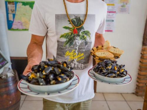 a man is holding two bowls of olives at Mobil-home 26m² 6 pers avec terrasse et salon de jardin - API-1-52-655 in Sainte-Eulalie-en-Born
