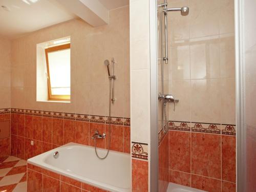 Chalet in Saalbach near Ski Lift & Sauna في سالباخ هينترغليم: حمام مع حوض استحمام ودش مع مرآة