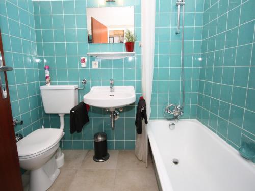 un bagno piastrellato blu con un water e un lavandino di Apartment Maria Alm near Hochkönig Ski Slopes a Maria Alm